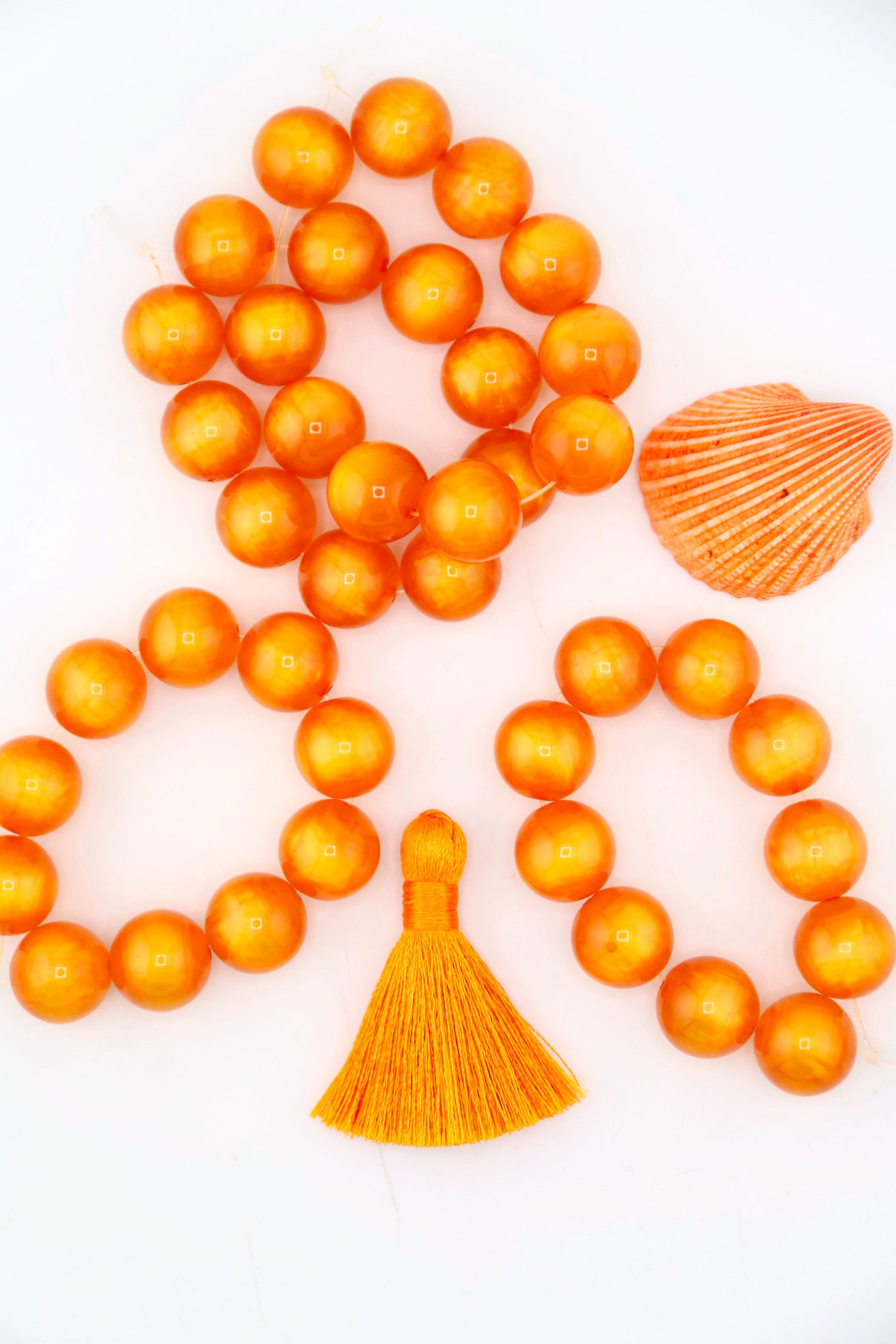 Flatlay of a strand of 12mm Orange Moon Glow Italian Poly Resin Round, for making Halloween jewelry