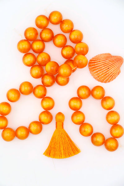 Flatlay of a strand of 12mm Orange Moon Glow Italian Poly Resin Round, for making Halloween jewelry