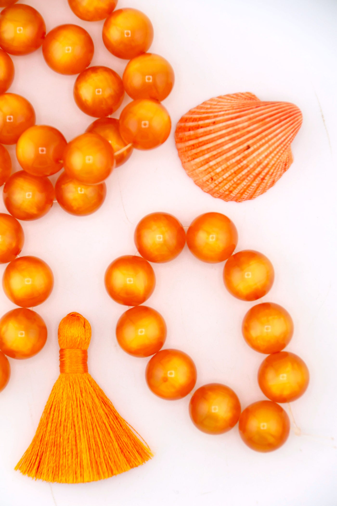 Flatlay of a strand of 12mm Orange Moon Glow Italian Poly Resin Round, for making Halloween jewelry