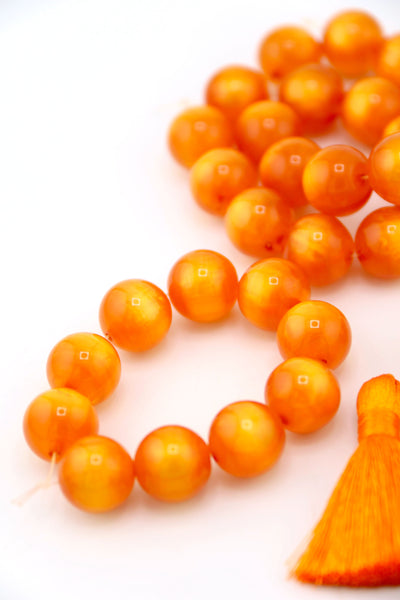 Flatlay of a strand of 12mm Orange Moon Glow Italian Poly Resin Round, for making Halloween jewelry