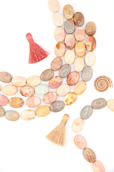 Close-up of Imperial Jasper oval beads, earthy gemstone tones, polished and strung together.