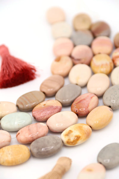 Close-up of Imperial Jasper oval beads, earthy gemstone tones, polished and strung together.