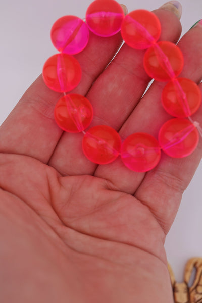 Neon pink German resin beads in an outstretched hand