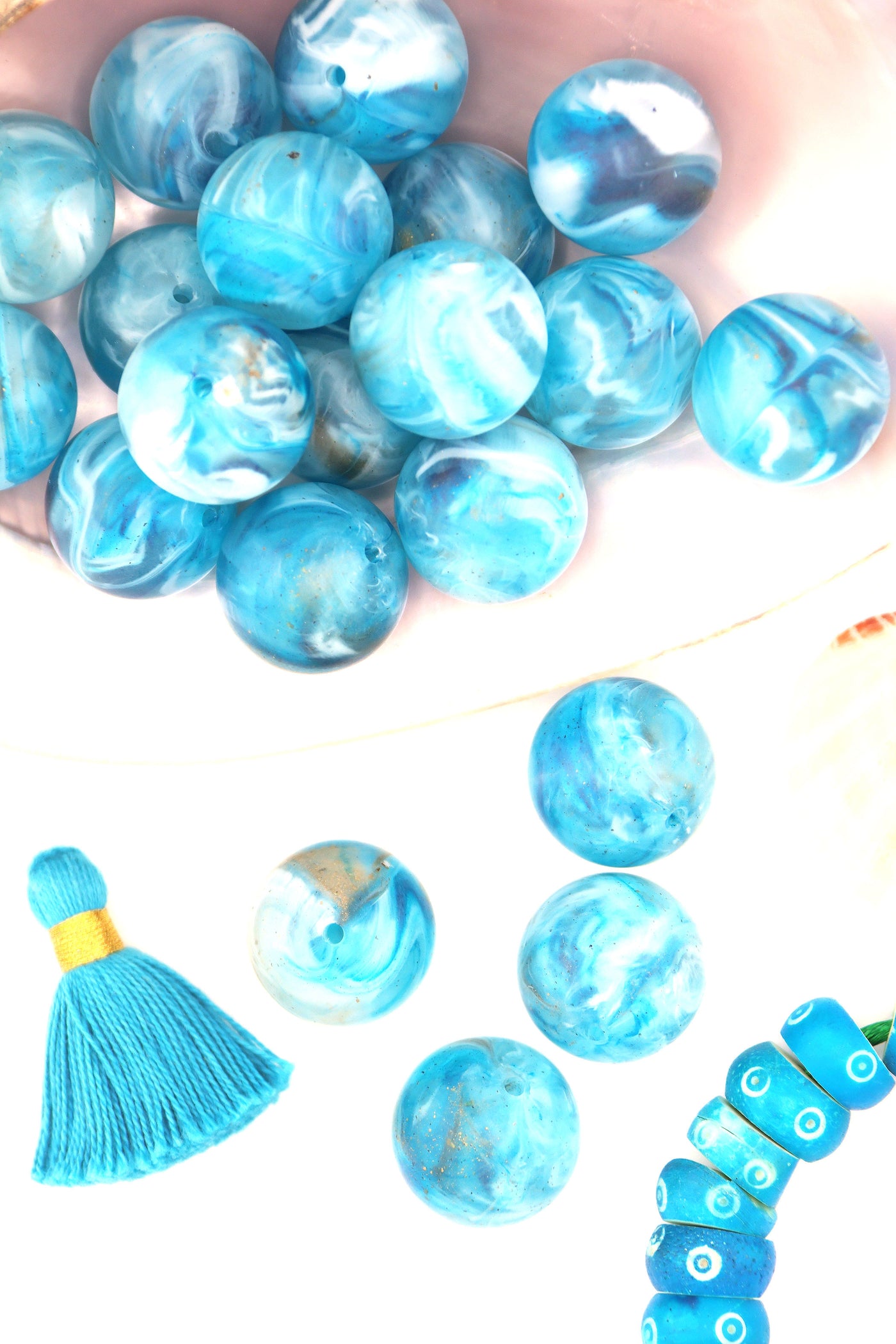 Turquoise blue swirly beads that look like earth, sitting in a large shell, with a tassel.