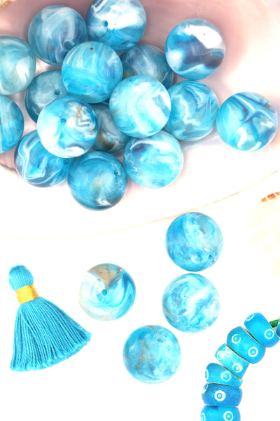 Turquoise blue swirly beads that look like earth, sitting in a large shell, with a tassel.