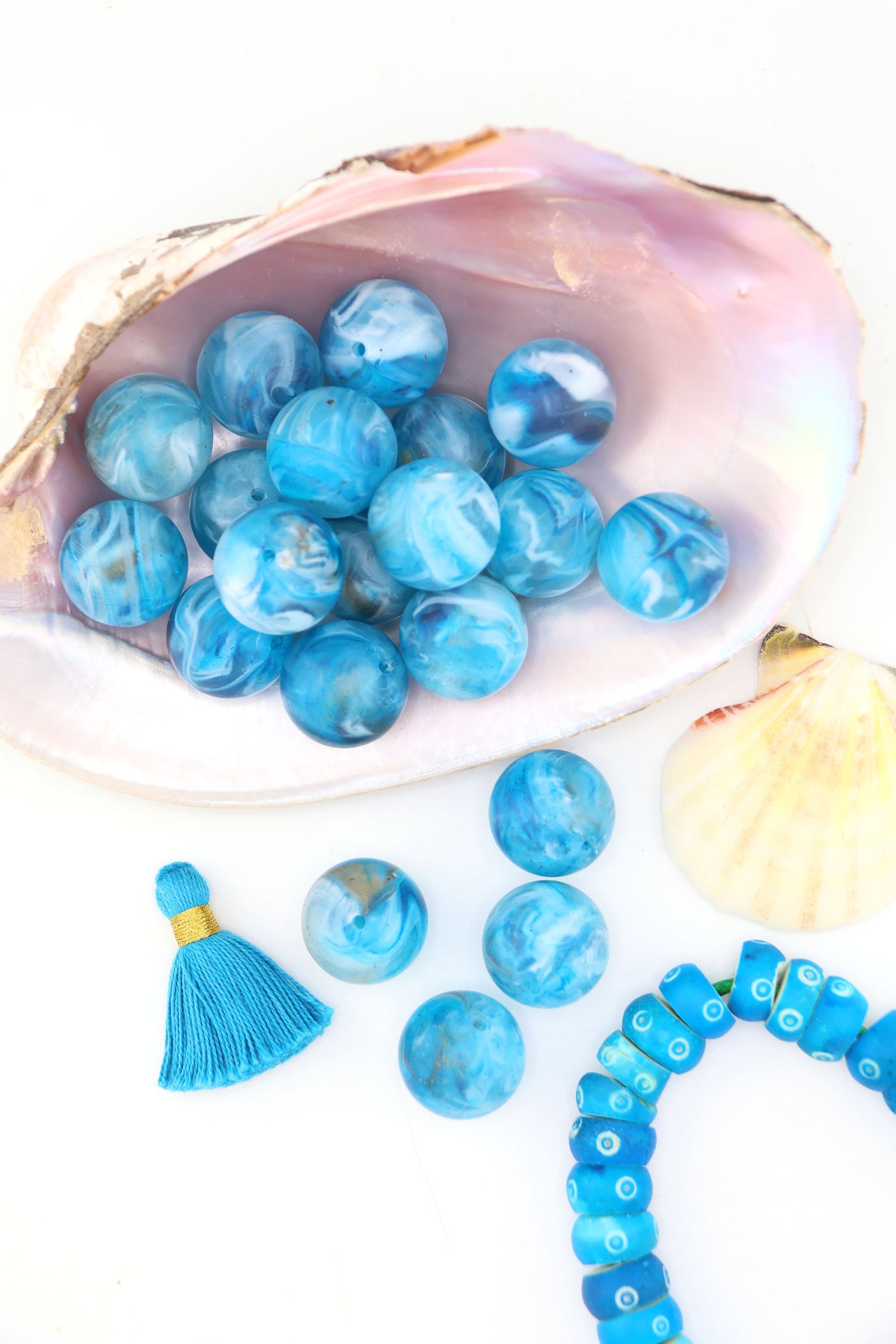 Turquoise blue swirly beads that look like earth, sitting in a large shell, with a tassel.