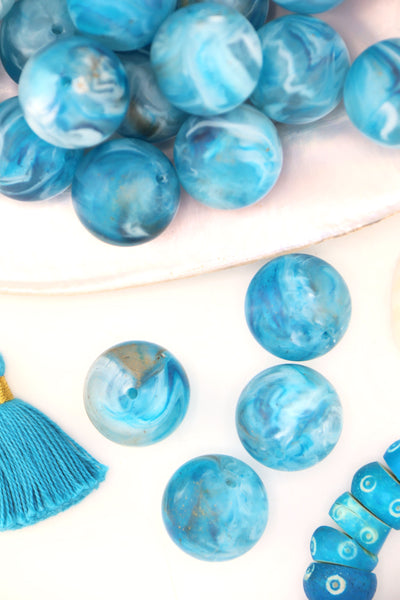 Turquoise blue swirly beads that look like earth, sitting in a large shell, with a tassel.