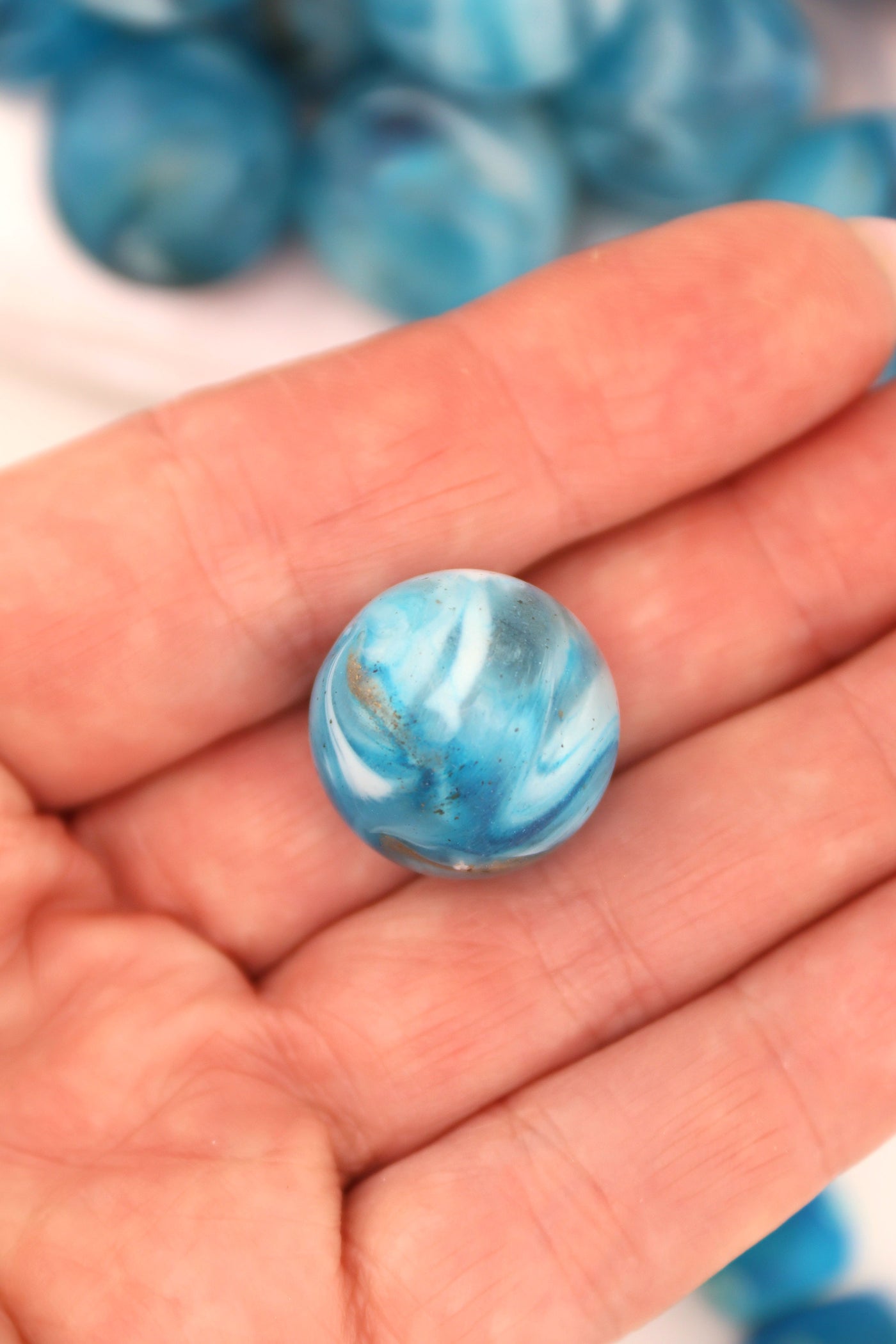 A large single blue swirly bead that looks like Mother Earth, sitting in the palm of a hand. 