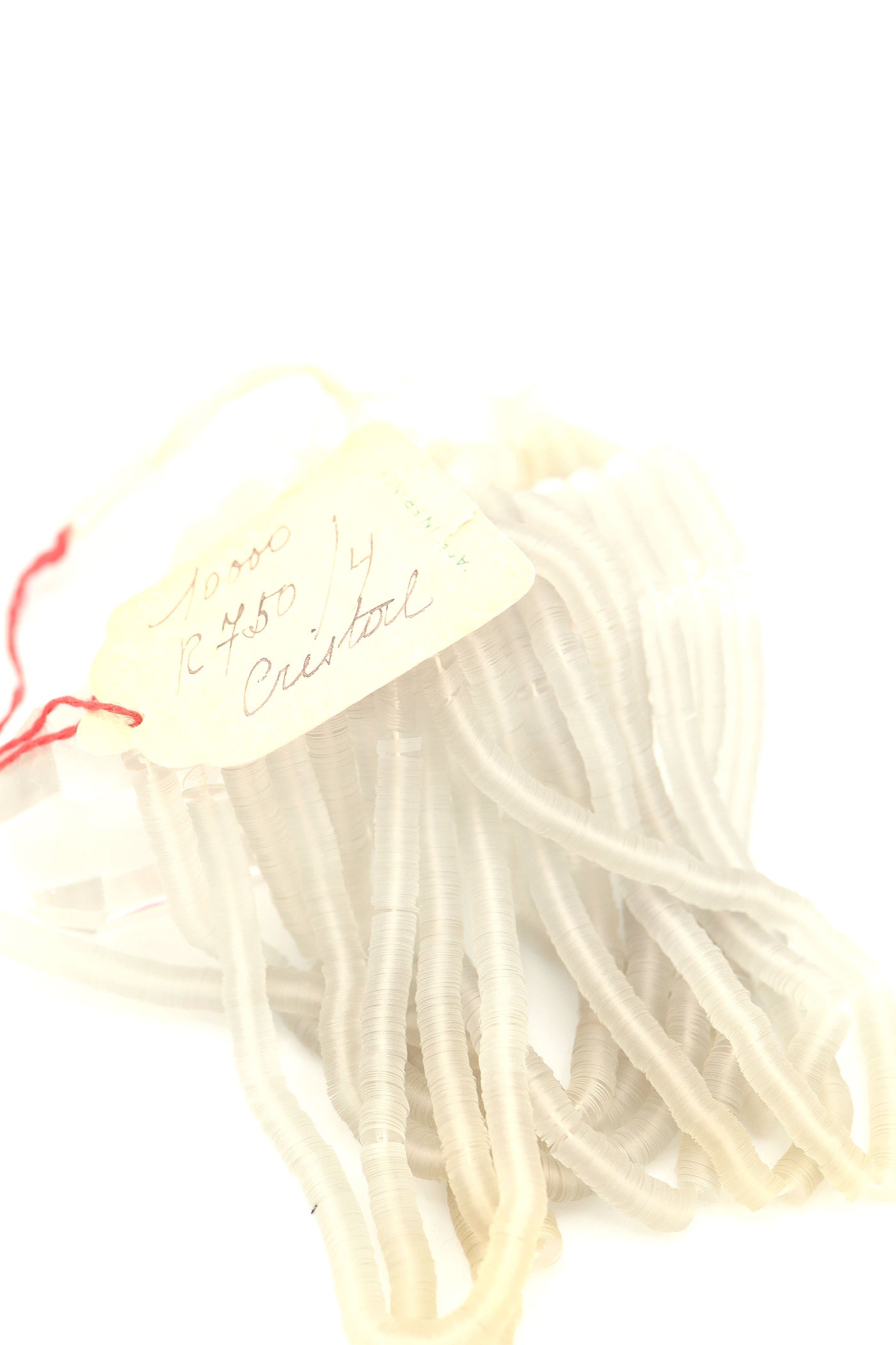 Hank of clear grey vintage French sequins draped so their iridescent faces are showing, and the vintage tag with handwriting.