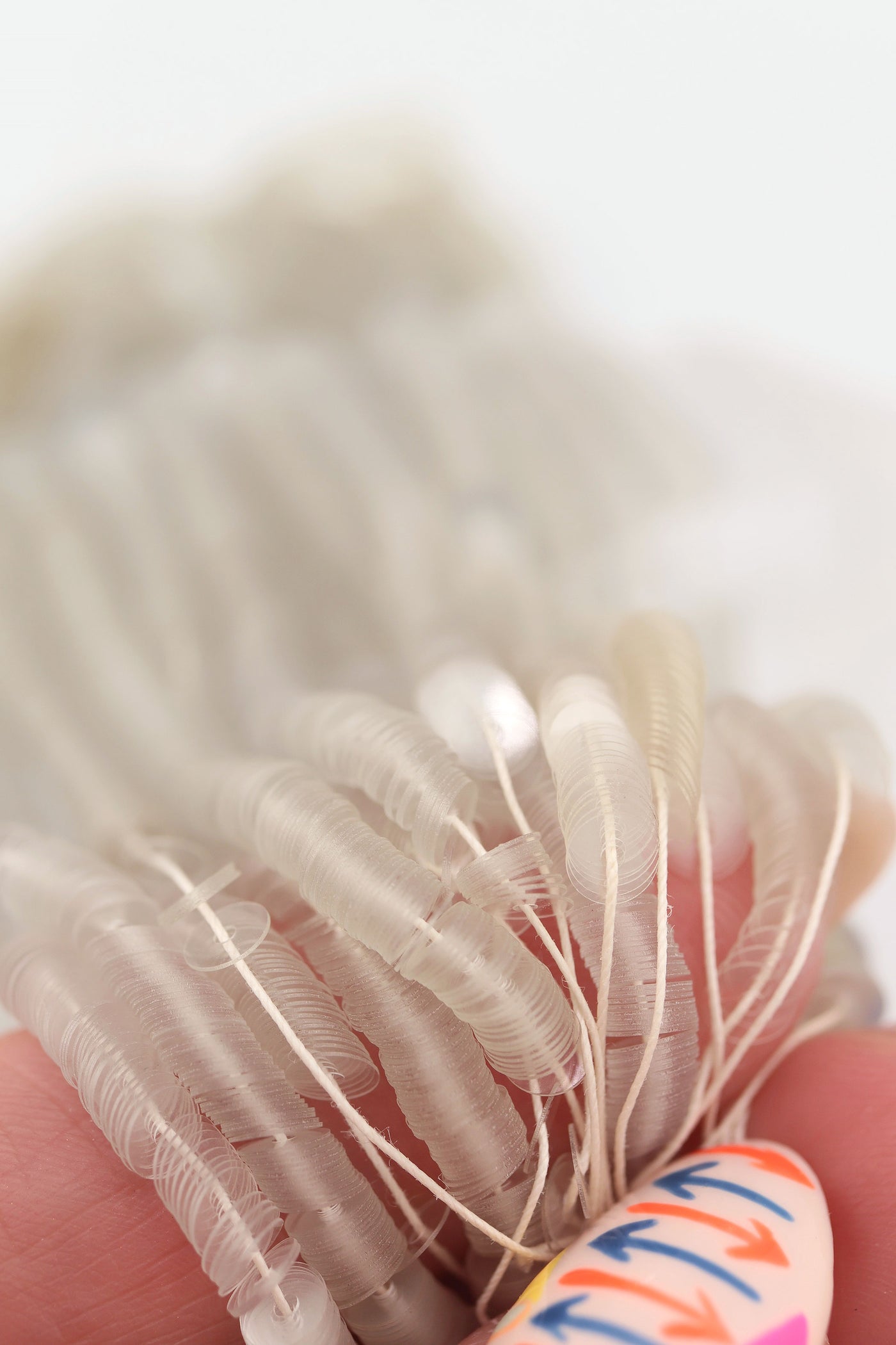 Hank of clear grey vintage French sequins draped so their iridescent faces are showing.