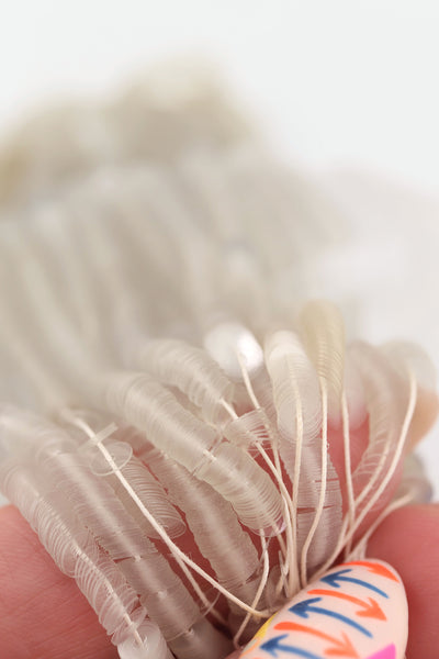 Hank of clear grey vintage French sequins draped so their iridescent faces are showing.