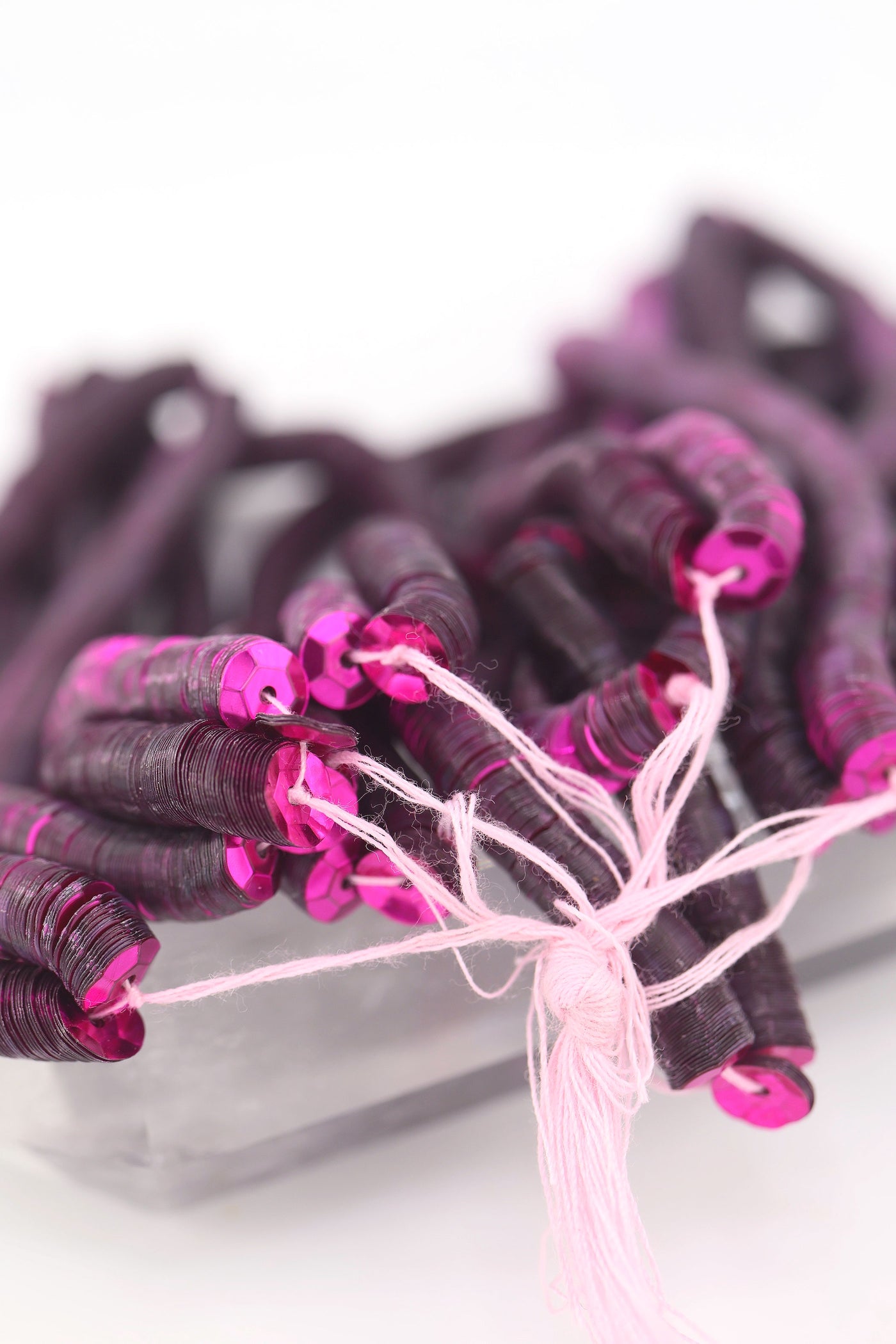 Close-up of burgundy red sequins strung on a strand, sparkling with a glossy jewel-toned finish.