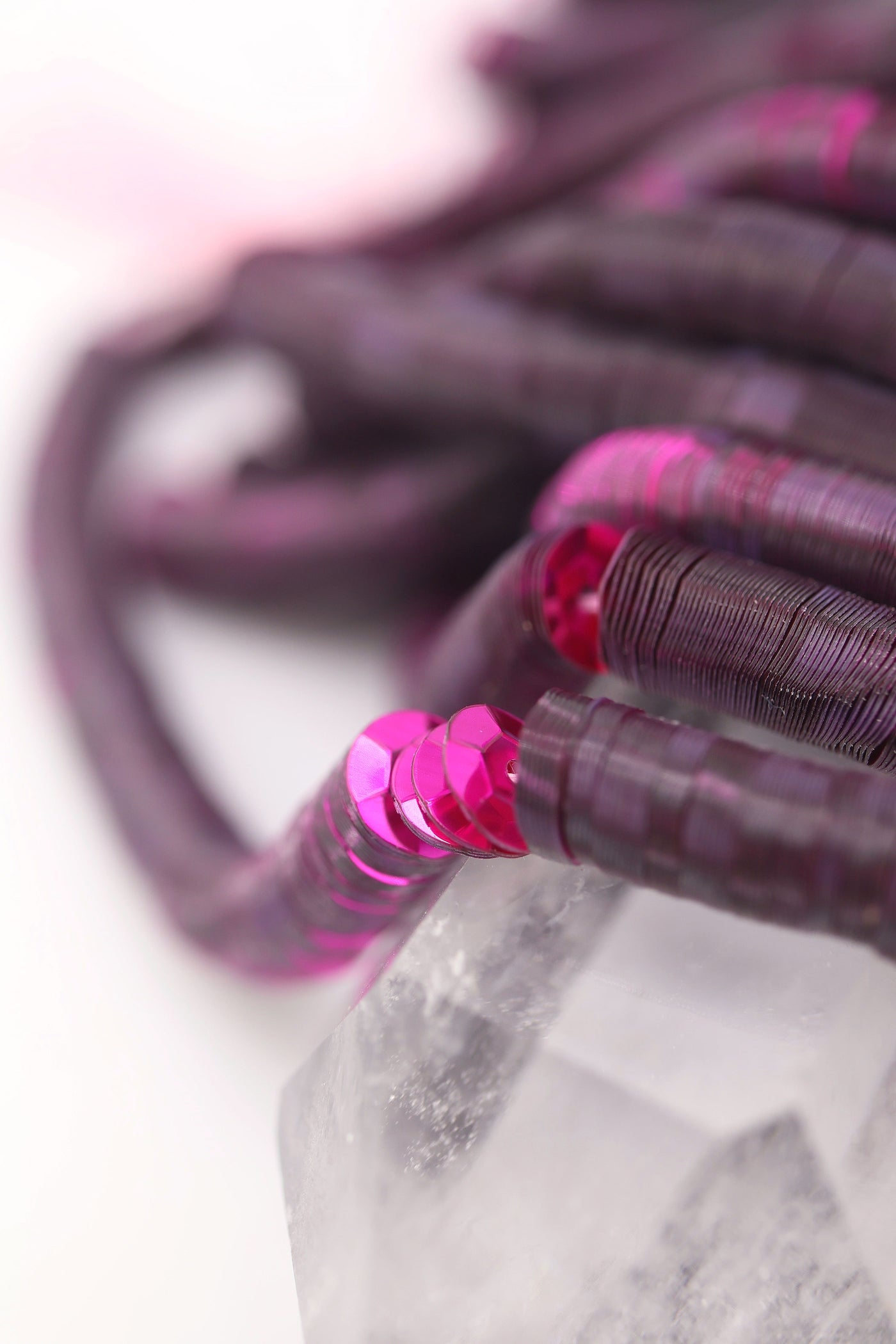 Close-up of burgundy red sequins strung on a strand, sparkling with a glossy jewel-toned finish.