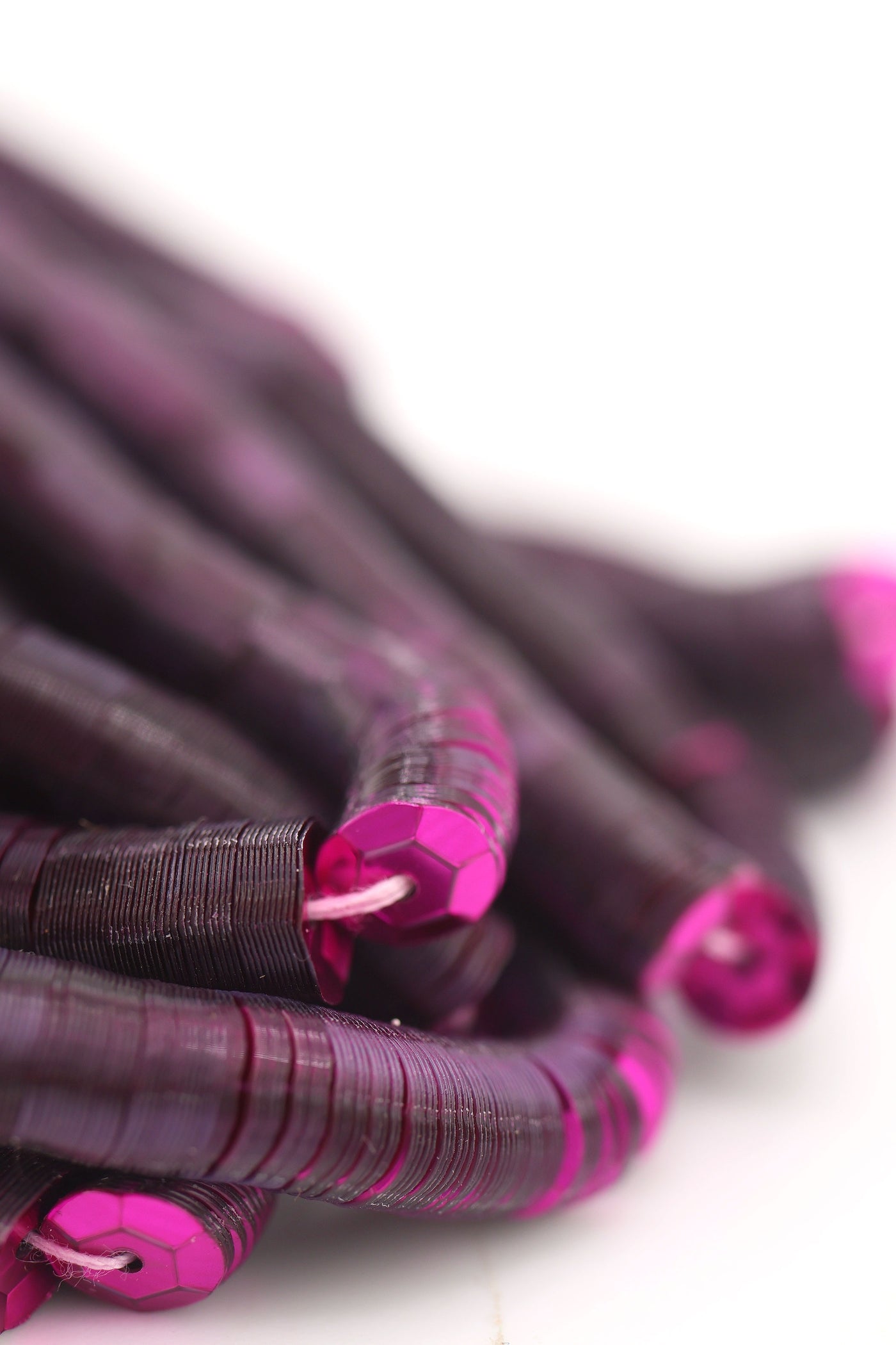 Close-up of burgundy red sequins strung on a strand, sparkling with a glossy jewel-toned finish.