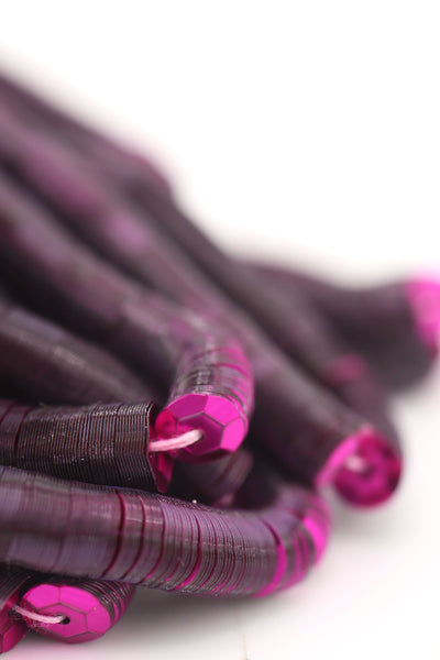 Close-up of burgundy red sequins strung on a strand, sparkling with a glossy jewel-toned finish.