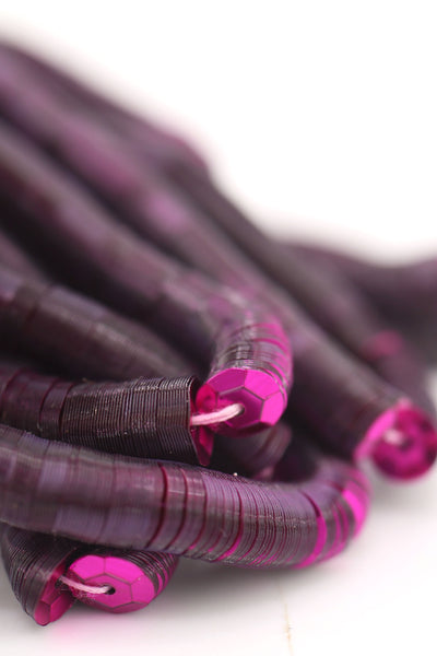 Close-up of burgundy red sequins strung on a strand, sparkling with a glossy jewel-toned finish.