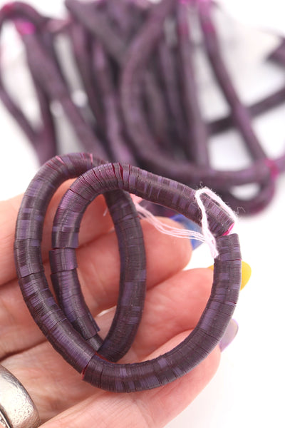 Hand holding teal vintage sequins, showing their delicate shine and flat round shape.