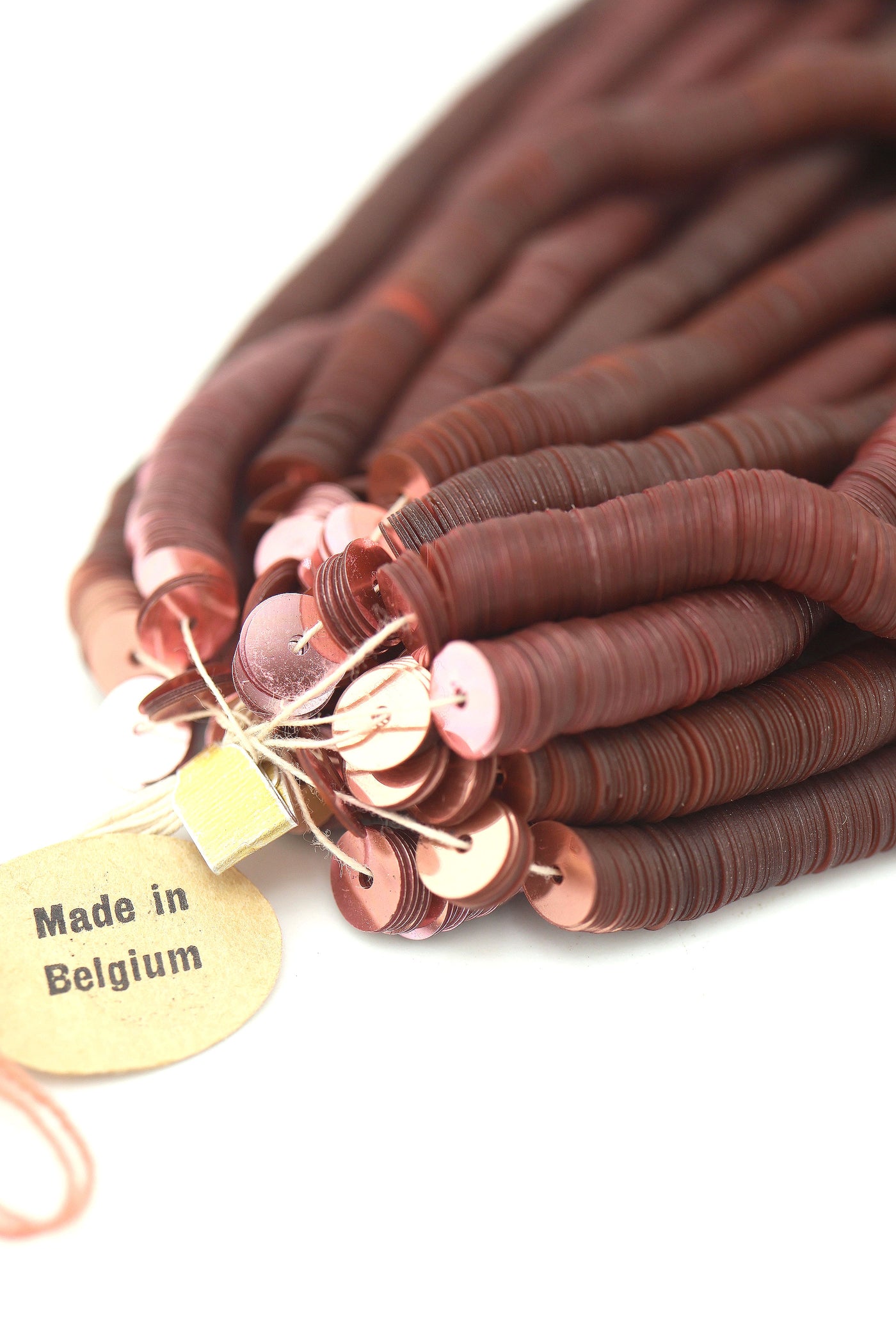 Close-up of vintage dusty rose sequins strung on a strand, sparkling with a glossy jewel-toned finish.