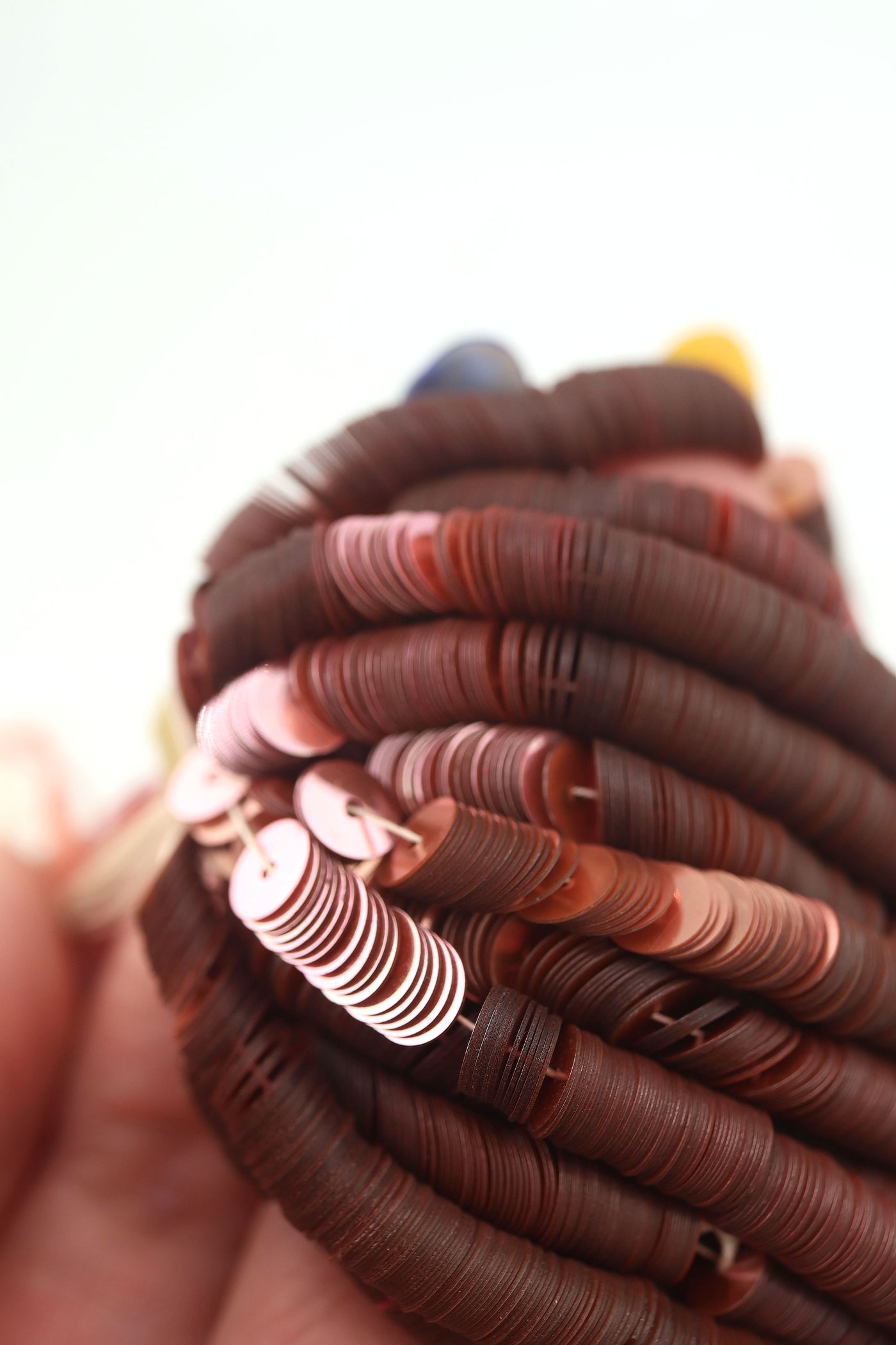 Close-up of vintage dusty rose sequins strung on a strand, sparkling with a glossy jewel-toned finish.
