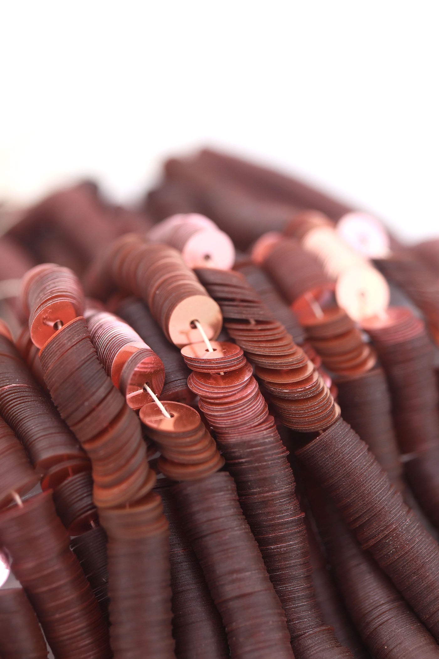 Close-up of vintage dusty rose sequins strung on a strand, sparkling with a glossy jewel-toned finish.