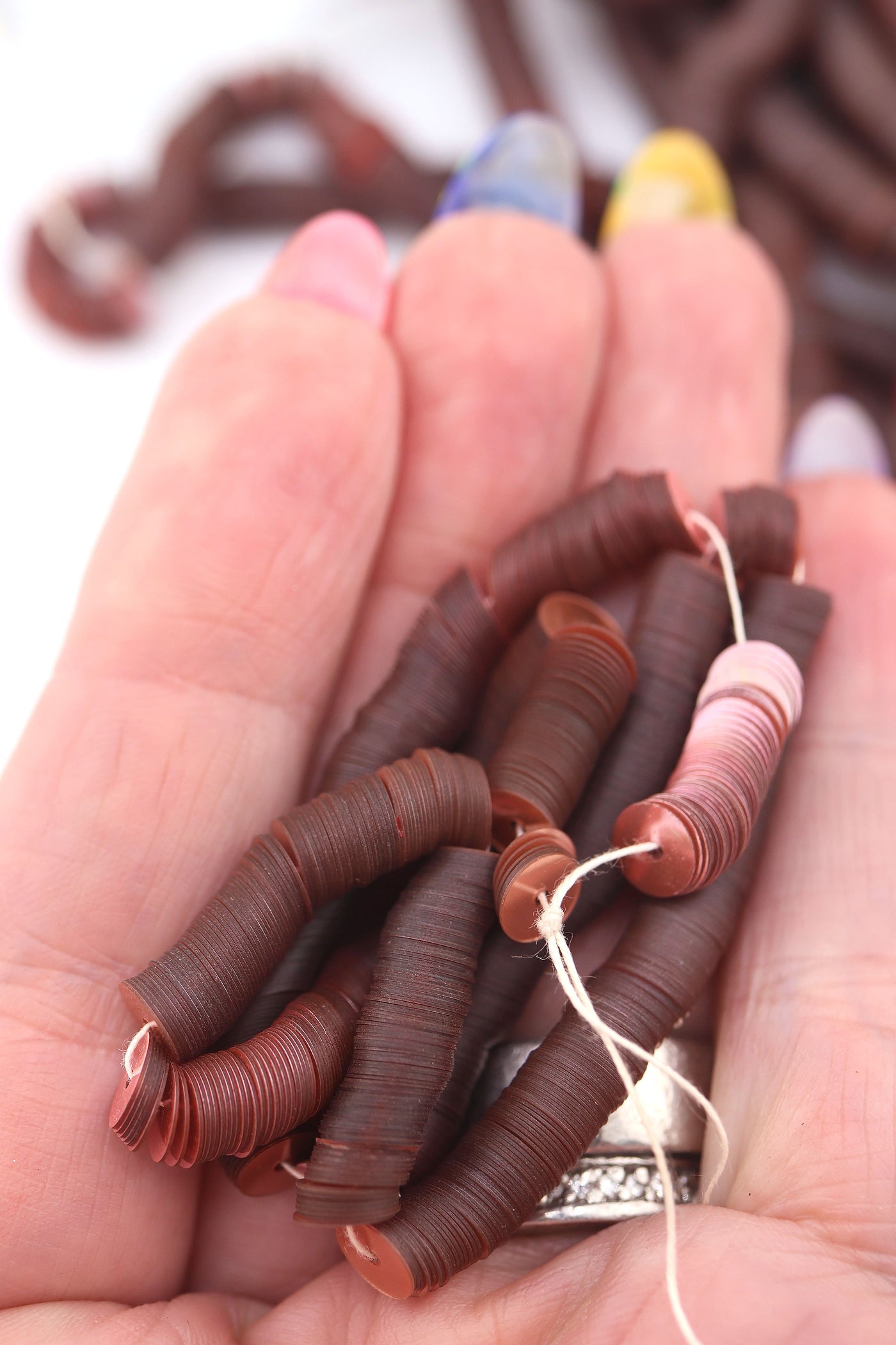 Hand holding dusty rose vintage sequins, showing their delicate shine and flat round shape.