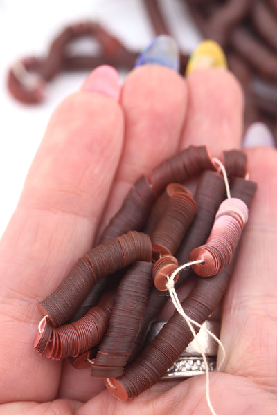 Hand holding dusty rose vintage sequins, showing their delicate shine and flat round shape.