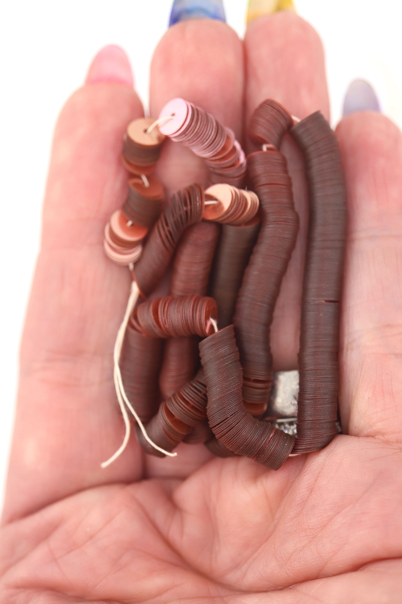 Hand holding dusty rose vintage sequins, showing their delicate shine and flat round shape.