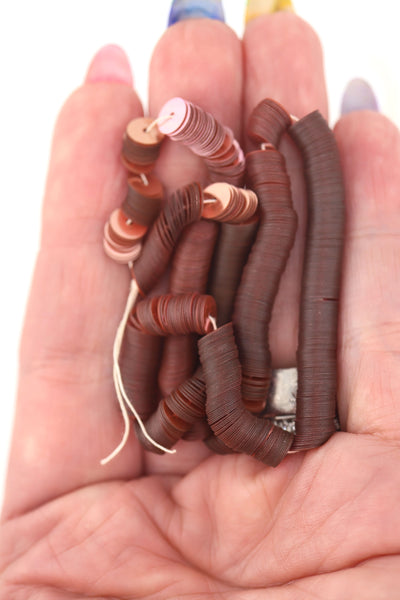 Hand holding dusty rose vintage sequins, showing their delicate shine and flat round shape.