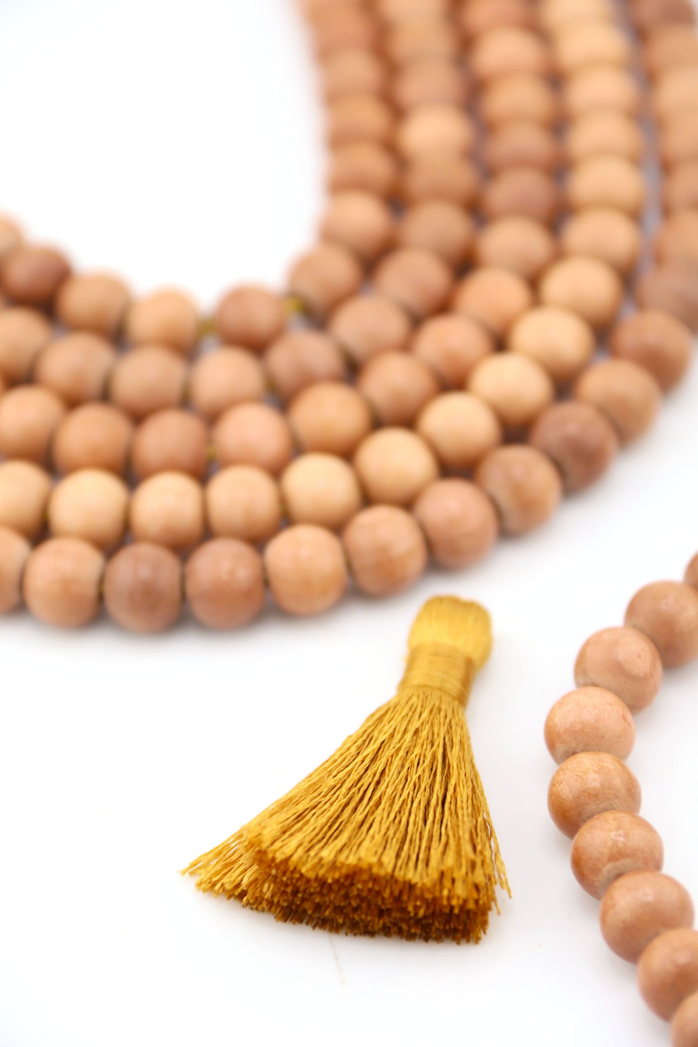 Strands of 8mm round wood beads in natural warm tones, handcrafted in India, styled with tassel and crystal accent.