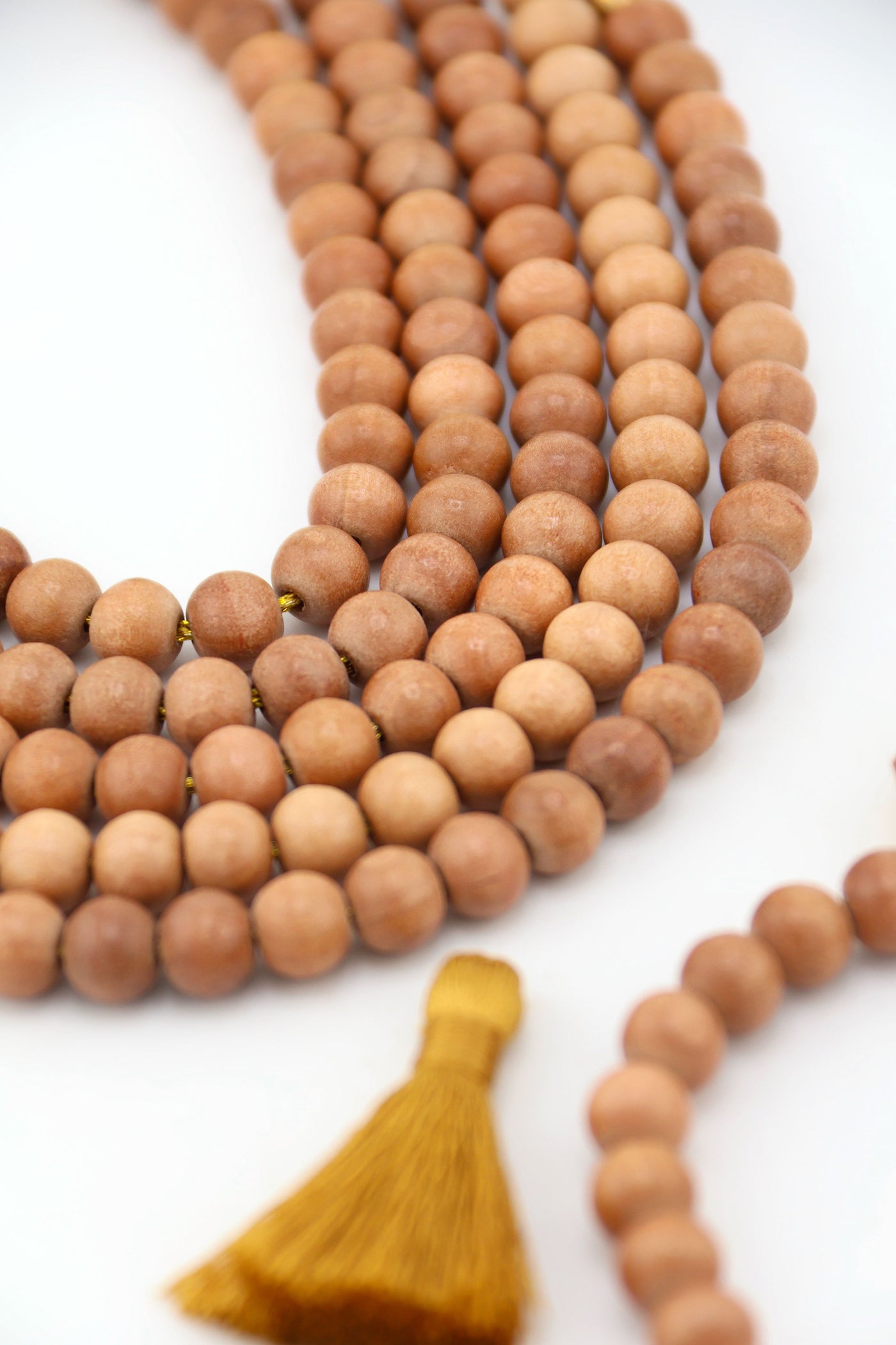 Strands of 8mm round wood beads in natural warm tones, handcrafted in India, styled with tassel and crystal accent.