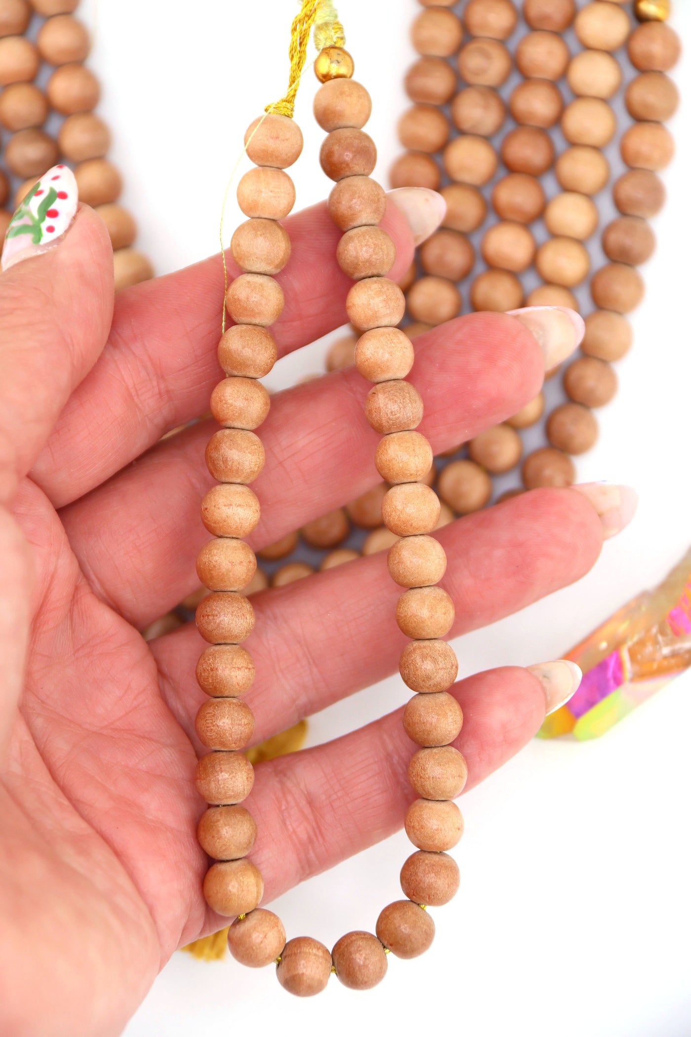 Hand holding a strand of 8mm round wood beads in natural finish, lightweight beads made in India