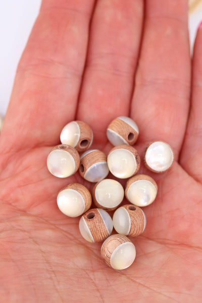 Loose Rosewood inlaid with Mother of Pearl beads, in the palm of a hand