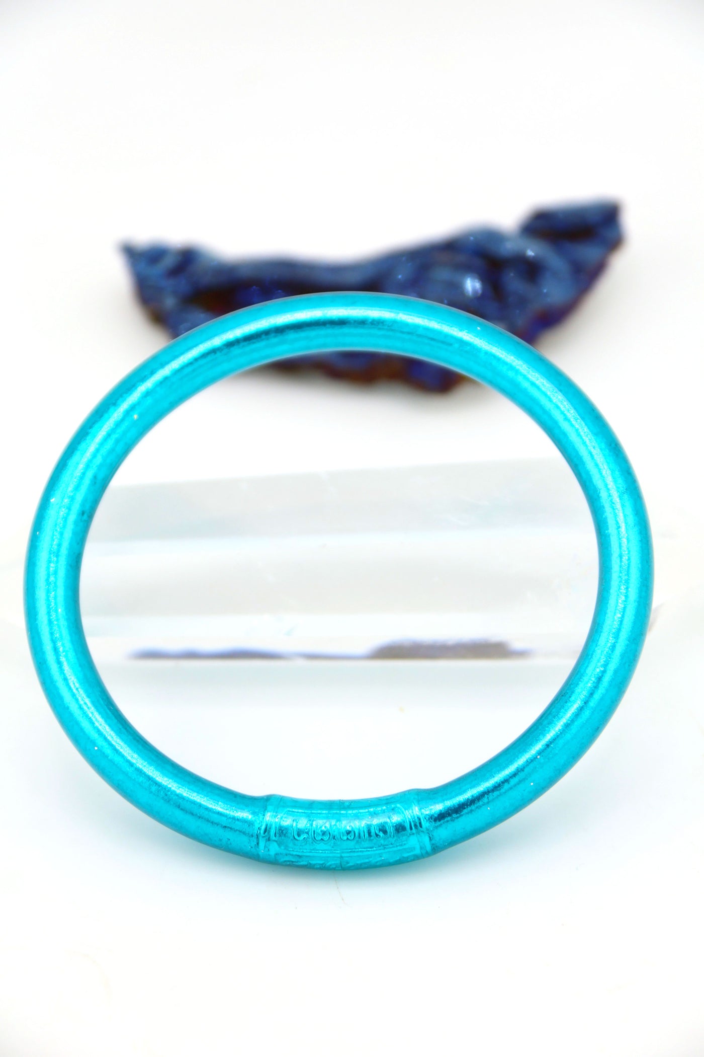 Close-up of Aqua Luxe Thai Mantra Bangles, thicker 8mm style in glowing aqua blue, worn on wrist.