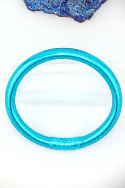 Close-up of Aqua Luxe Thai Mantra Bangles, thicker 8mm style in glowing aqua blue, worn on wrist.