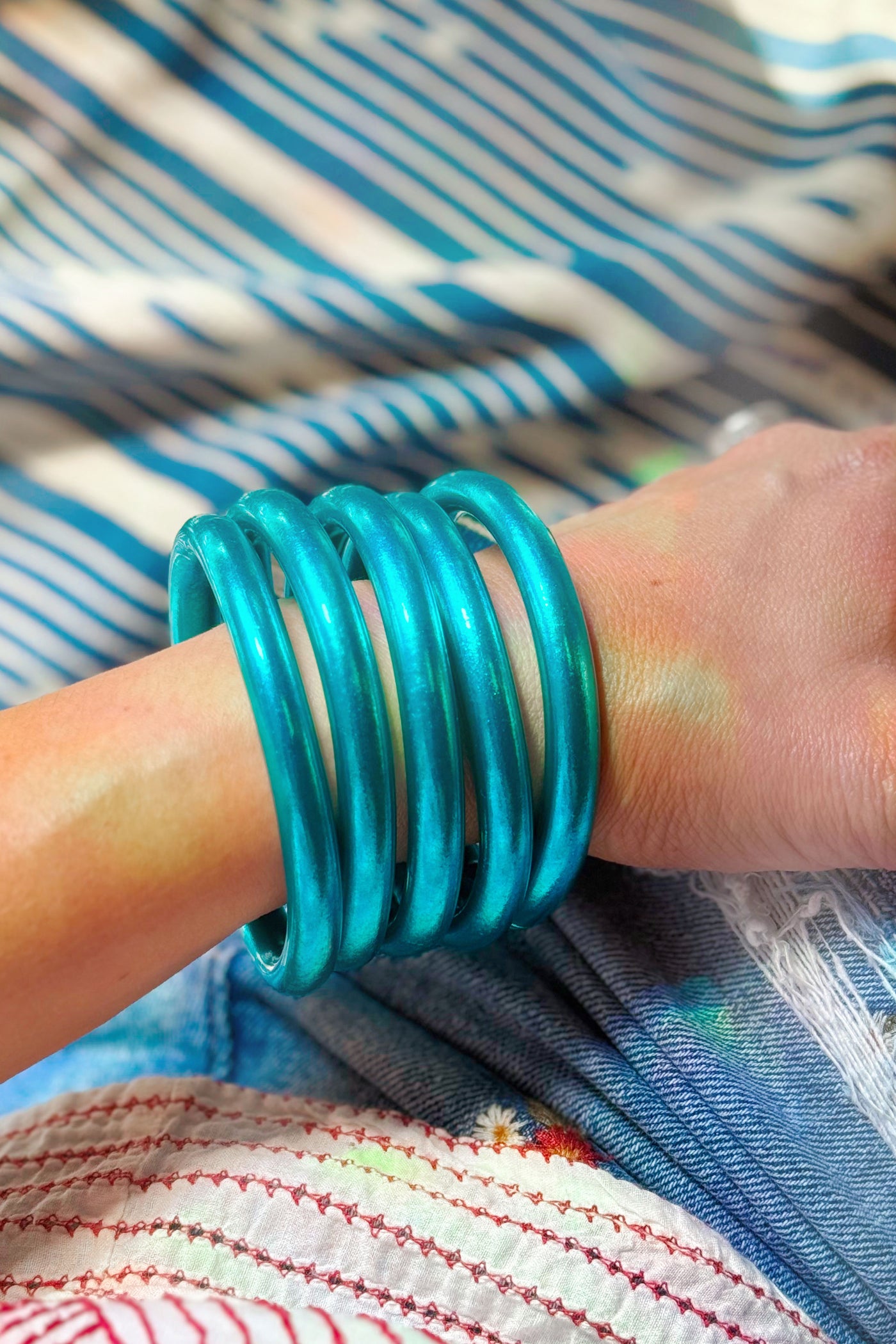 Stack of Aqua Luxe Thai Mantra Bangles on wrist, chunky 8mm temple bracelets in radiant aqua blue with glossy finish.