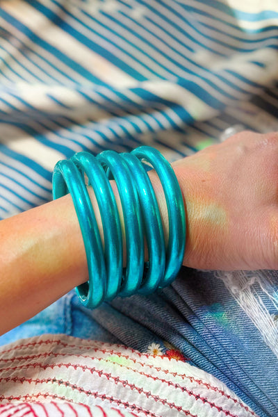 Stack of Aqua Luxe Thai Mantra Bangles on wrist, chunky 8mm temple bracelets in radiant aqua blue with glossy finish.