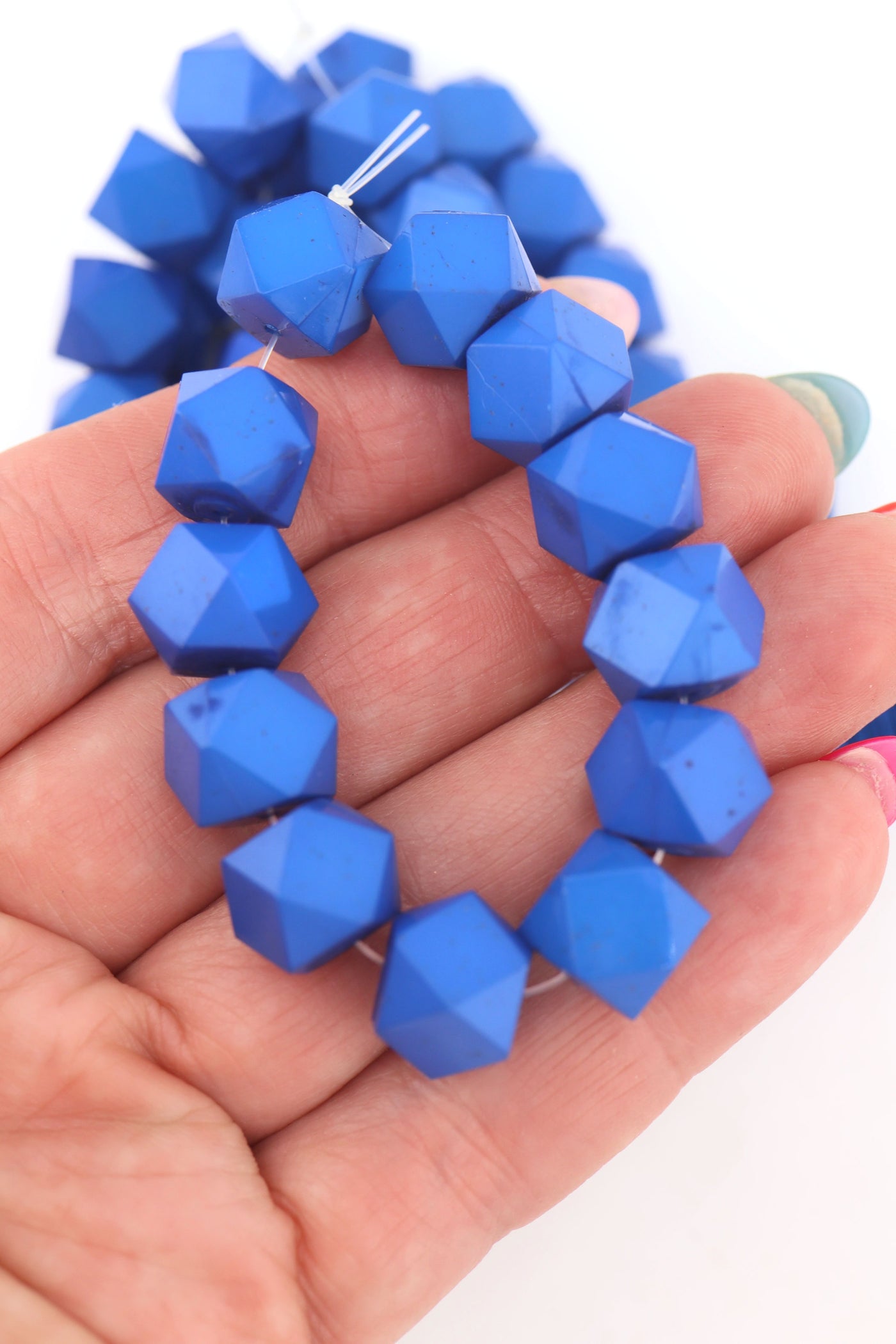 Classic Blue 12 Sided Faceted Cube Beads in an outstretched hand