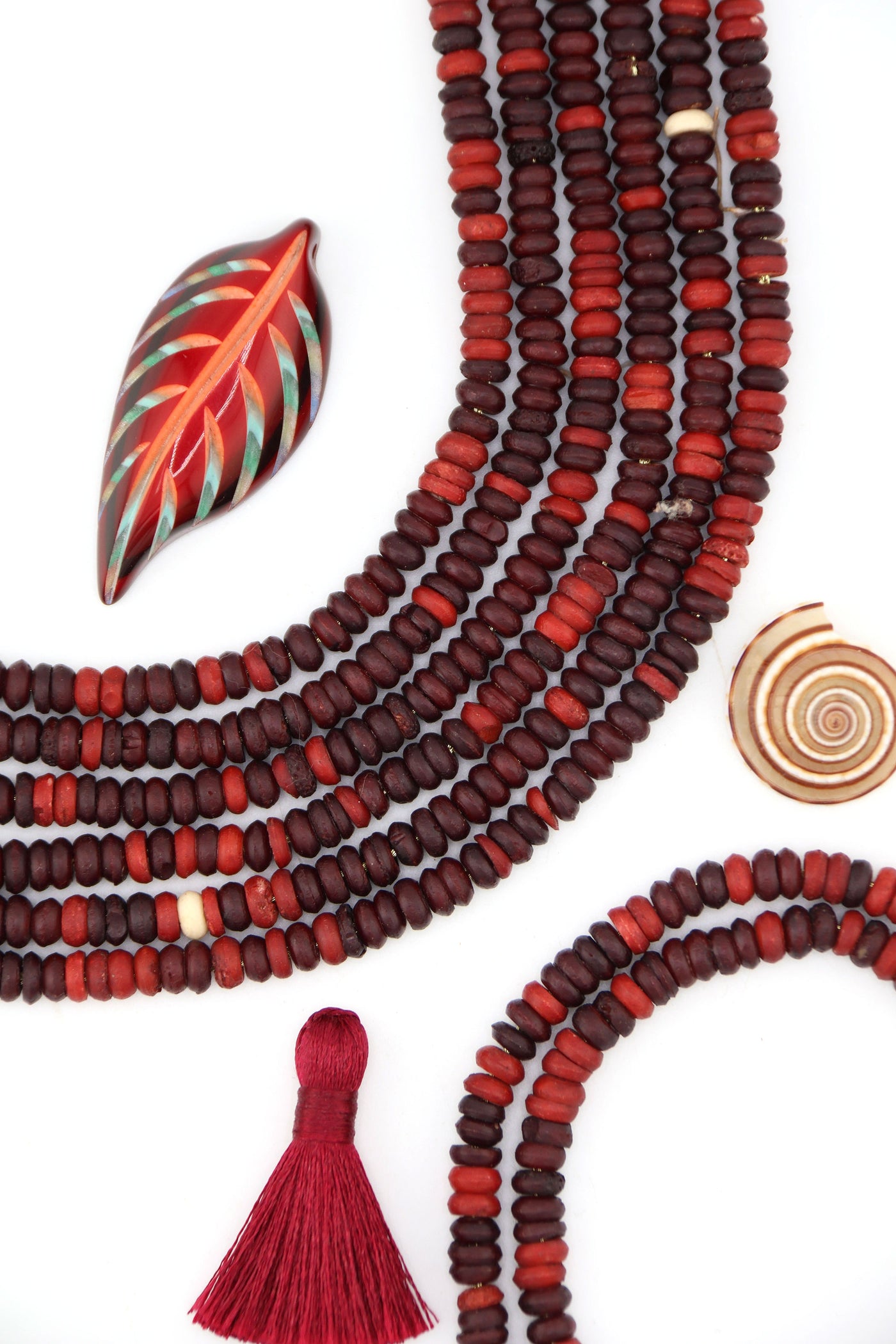 Ethically sourced burgundy bone heishi beads in warm fall tones, styled in layered strands.