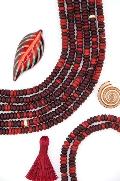 Ethically sourced burgundy bone heishi beads in warm fall tones, styled in layered strands.