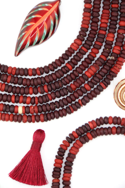 Close-up of small 6x3mm burgundy bone heishi beads with natural matte texture, handmade.