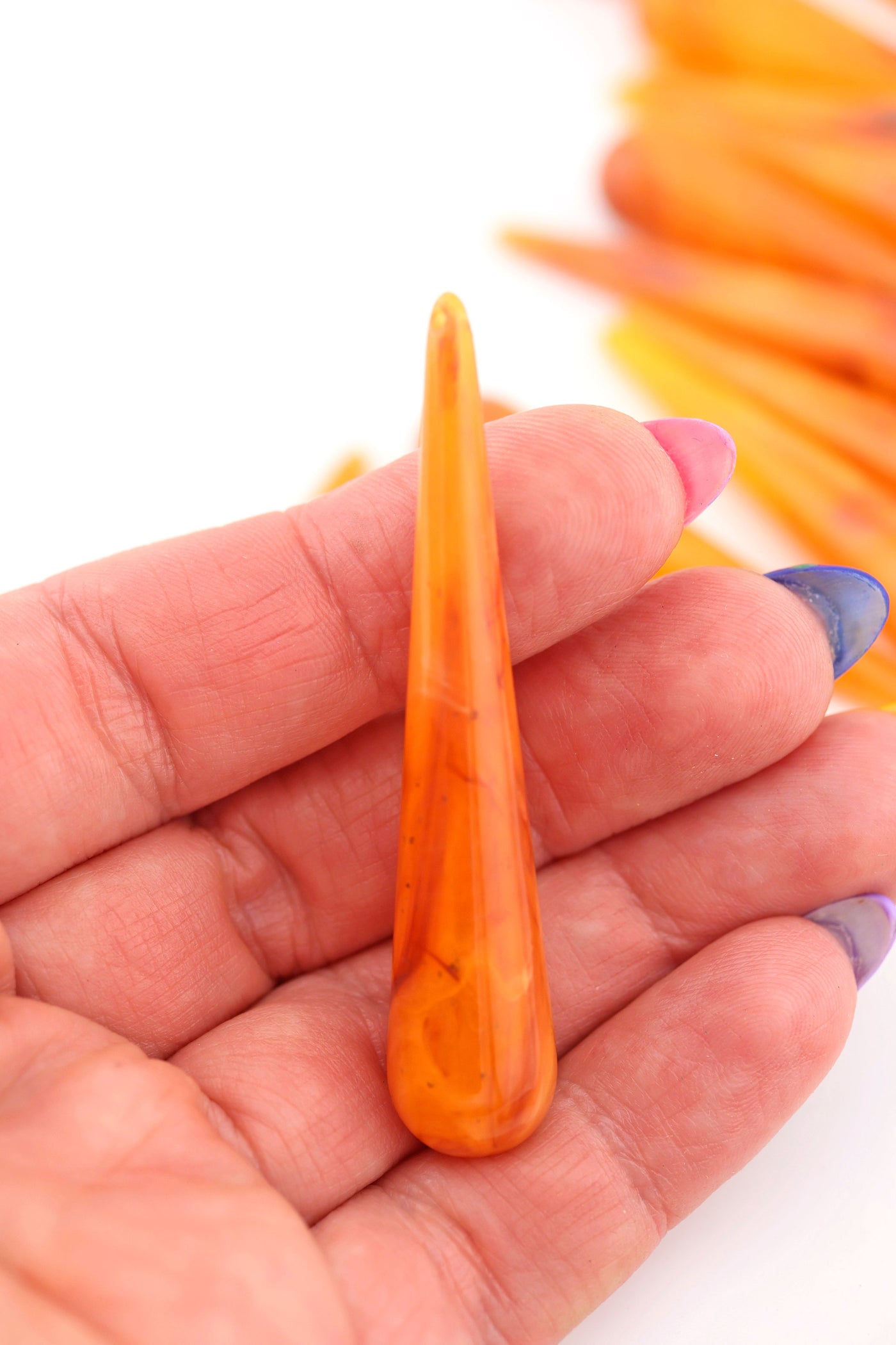 Orange teardrop bead in the palm of a hand