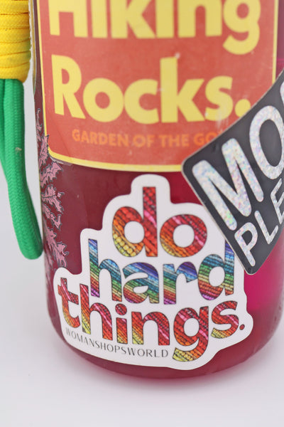 Vinyl sticker reading “do hard things” with rainbow bead-filled letters, applied to a maroon water bottle alongside other stickers. The colorful design stands out against the background.