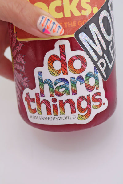 Vinyl sticker reading “do hard things” with rainbow bead-filled letters, applied to a maroon water bottle alongside other stickers. The colorful design stands out against the background.