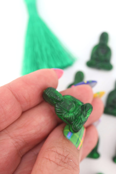 Hand holding a marbled green resin Buddha charm, for making yoga jewelry or spiritual malas.