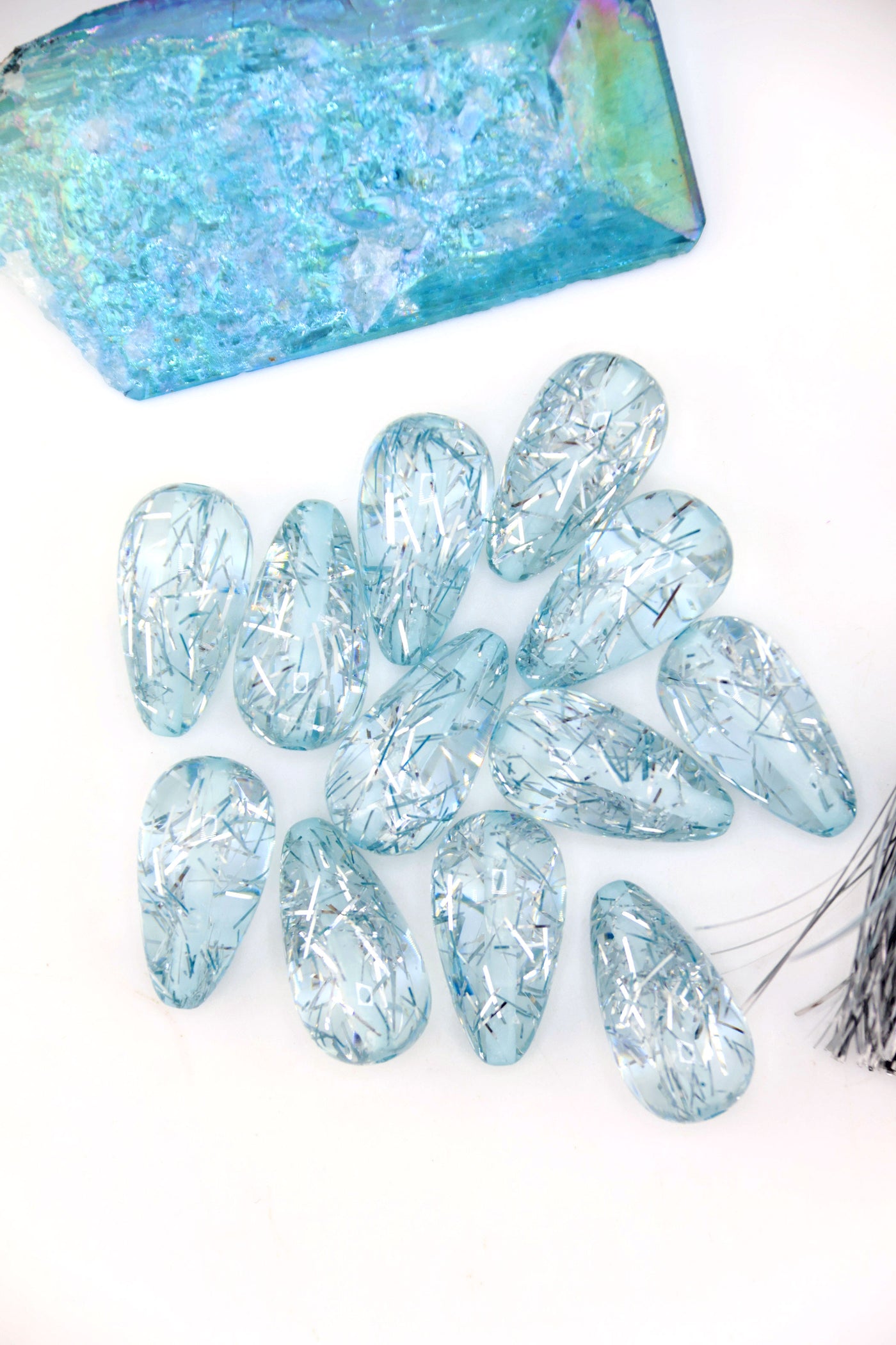 Collection of Ice Blue Glitter Italian Resin Teardrop Beads on a white background with a blue crystal