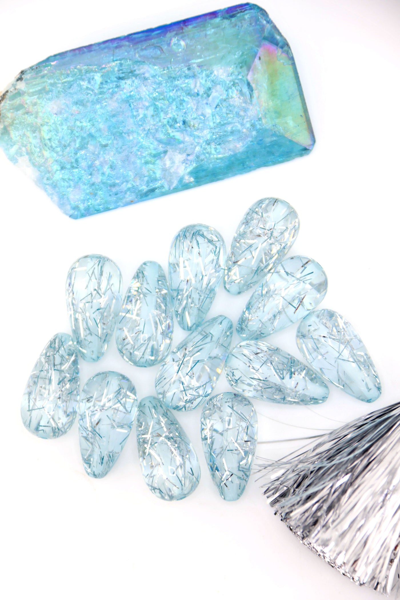 Collection of Ice Blue Glitter Italian Resin Teardrop Beads on a white background with a blue crystal