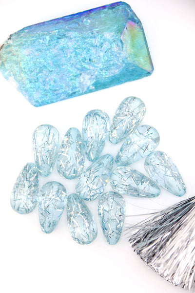 Collection of Ice Blue Glitter Italian Resin Teardrop Beads on a white background with a blue crystal