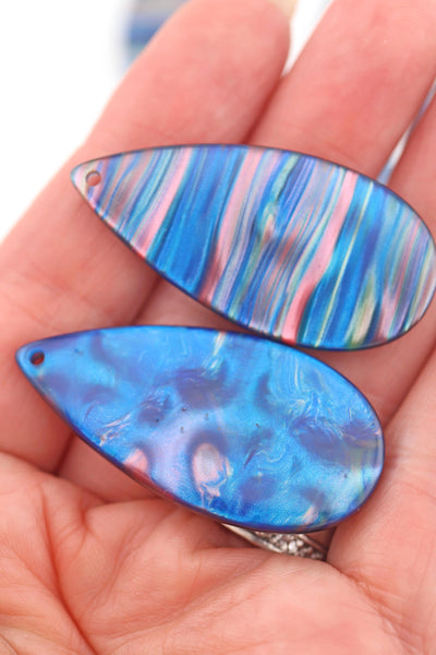 Hand holding 2 Blue Galaxy Waves Teardrop Laser Cut Italian Poly Resin Pendant 