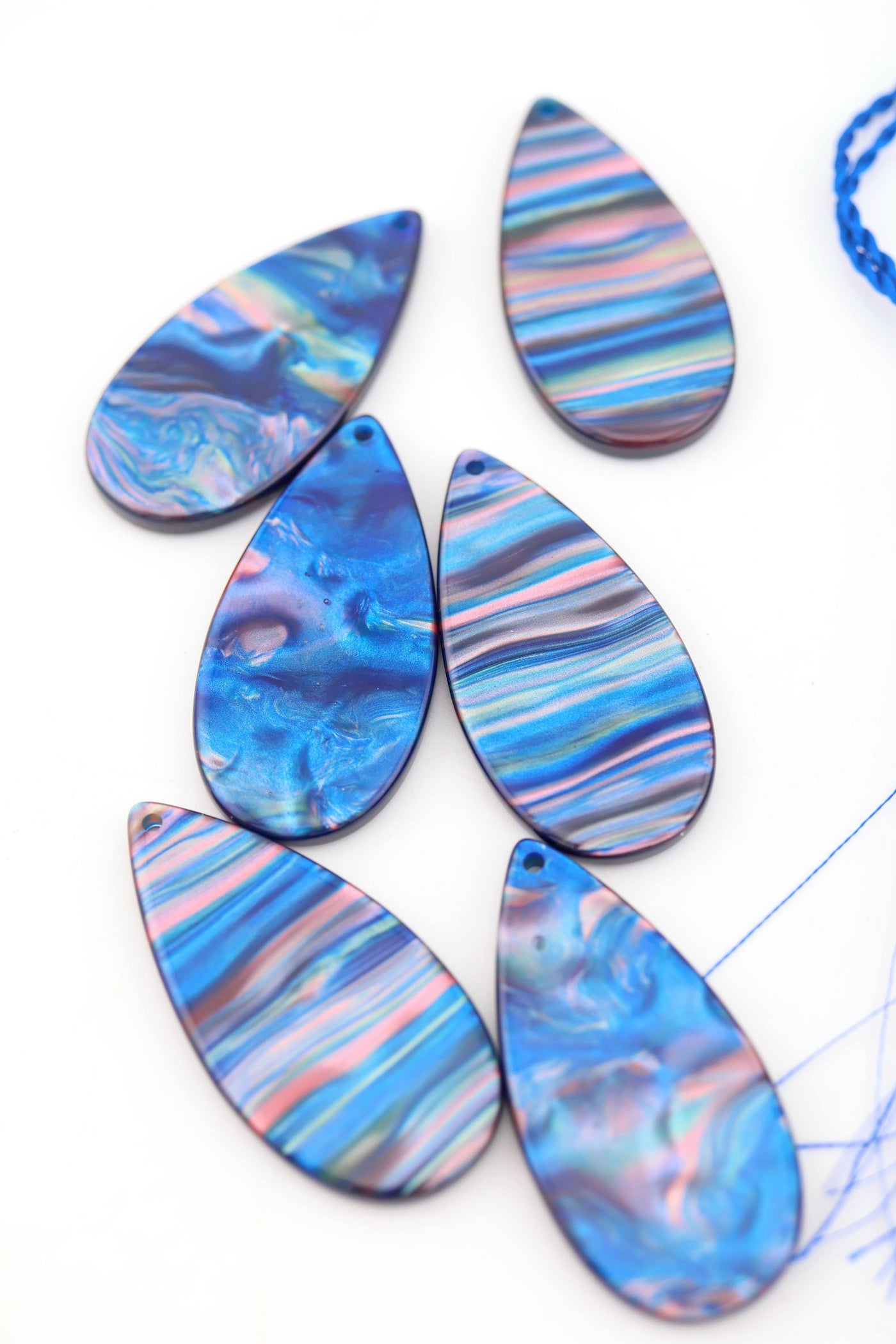 Flatlay of Blue Galaxy Waves Teardrop Laser Cut Italian Poly Resin Pendant 46mm against white background