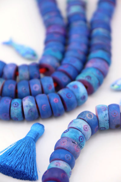 Strands of blue donut carved bone beads with bullseye details, chunky 14x7mm large-hole beads styled with tassel.